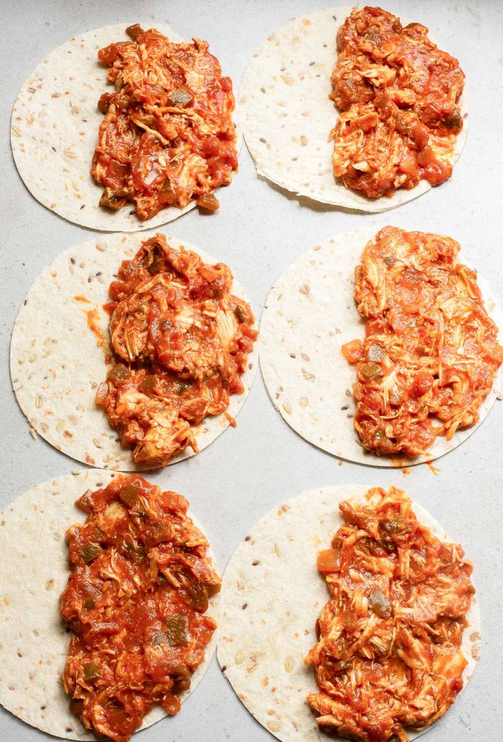 six tortillas on a baking sheet ready to be cooked and put in the oven