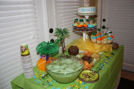 a green table topped with lots of desserts and cupcakes on top of it