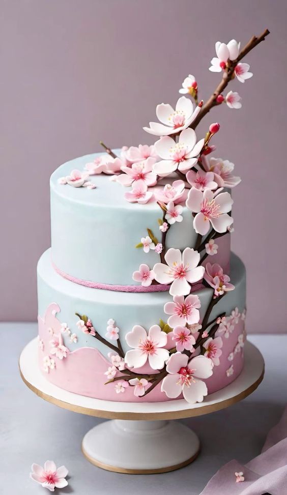 a three tiered cake with pink flowers on the top and blue icing around it