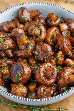 a bowl filled with cooked mushrooms on top of a wooden table