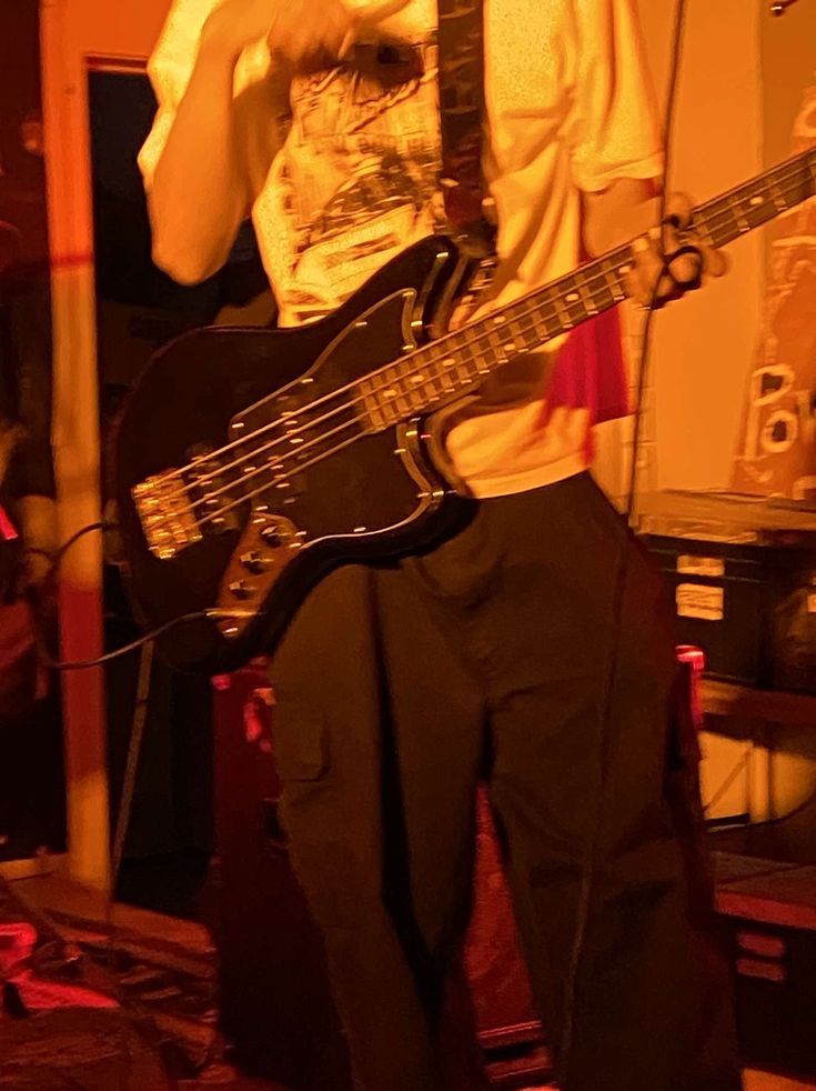 a man standing in front of a microphone while holding a guitar