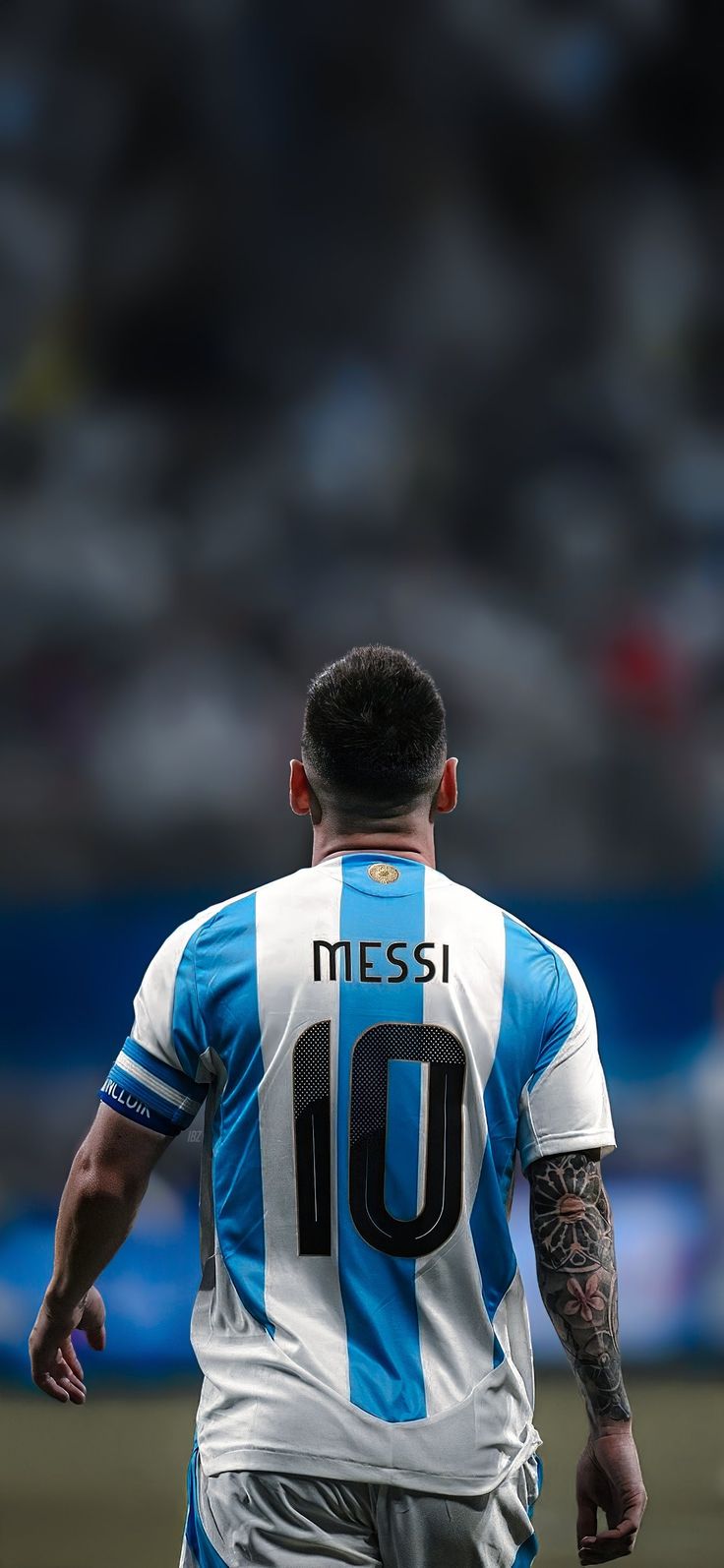 a soccer player in blue and white uniform on the field with his back to the camera