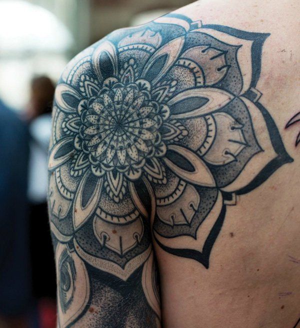 the back of a man's shoulder with a tattoo design on it