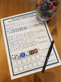 a wooden table topped with dices next to a glass filled with water and candy