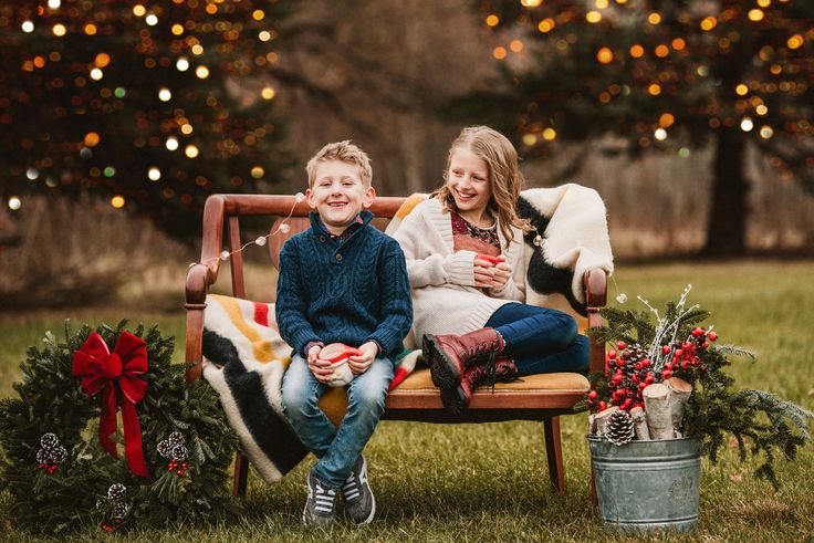 two children sitting on a bench with christmas decorations