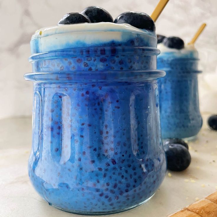 blueberry cheesecake in a glass jar with a wooden spoon next to it on a counter