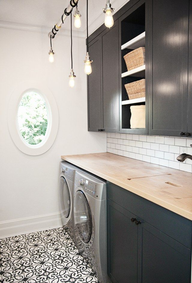 an image of a laundry room with grey cabinets and tile flooring on the walls