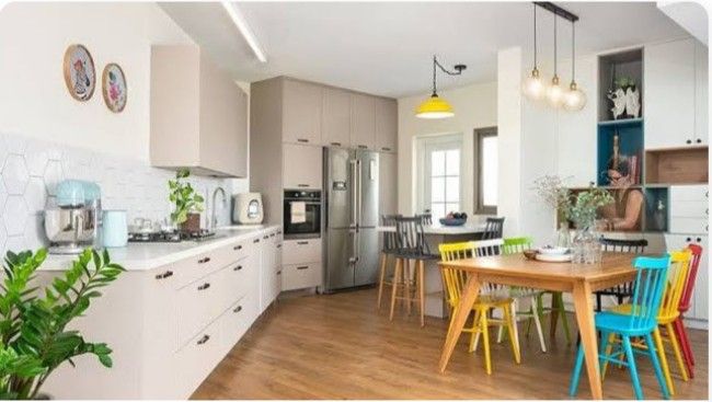 a kitchen filled with lots of colorful chairs and counter top next to a dining room table