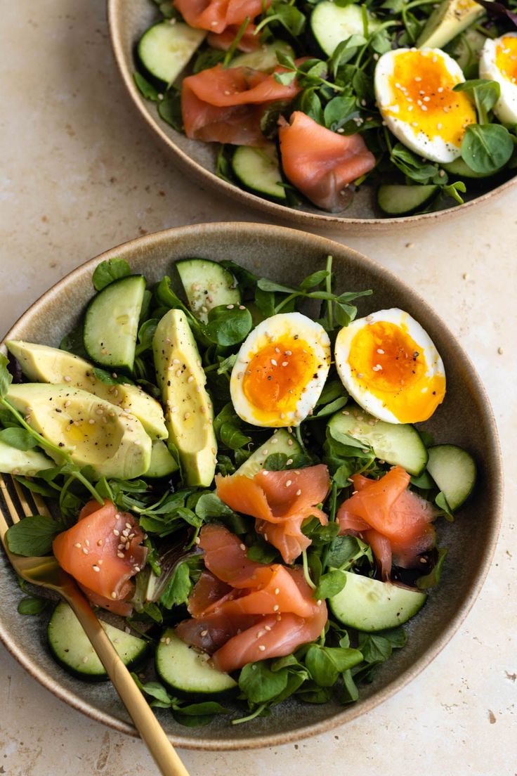 two bowls filled with cucumber, avocado and hard boiled egg salad