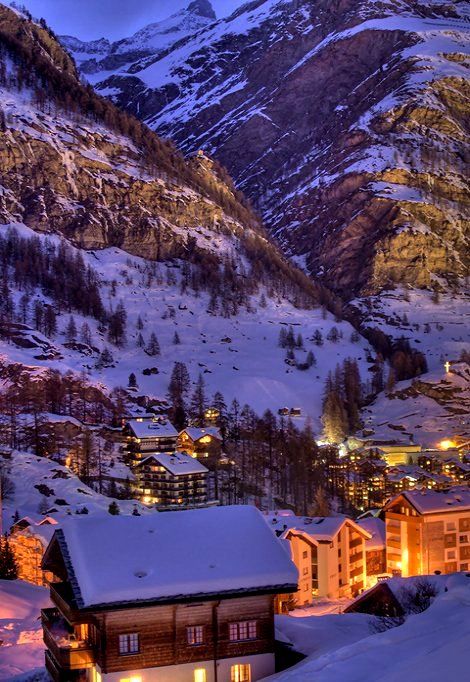 the mountains are covered in snow and lit up by lights at night, as well as buildings