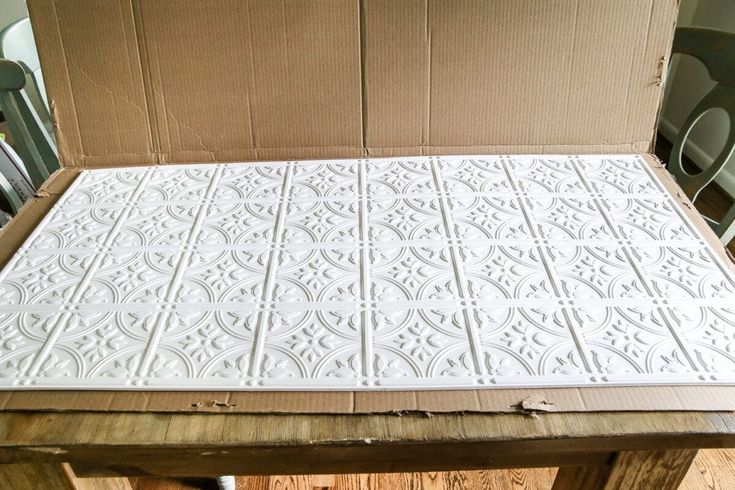 an open cardboard box sitting on top of a wooden table with chairs in the background