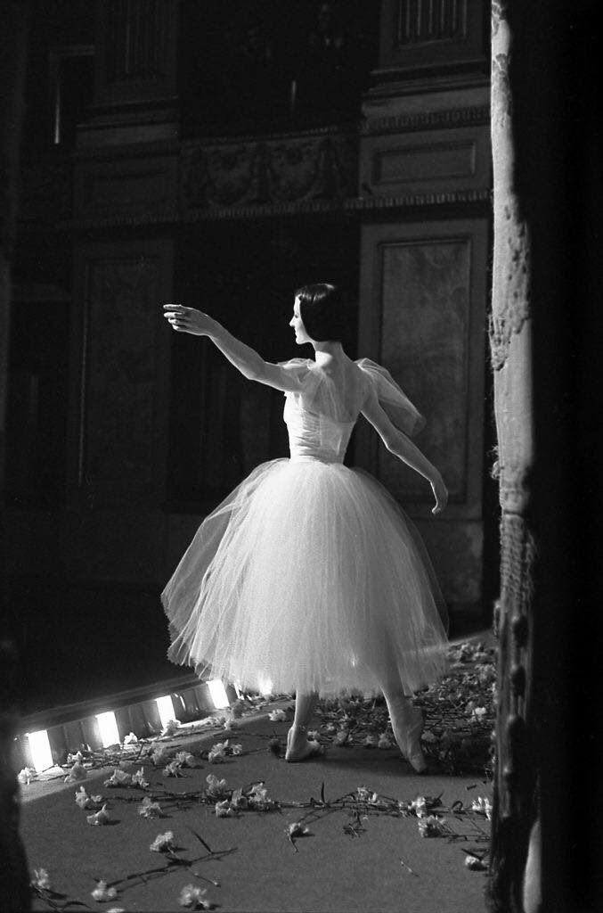 a black and white photo of a ballerina in a tutu skirt with her arms outstretched