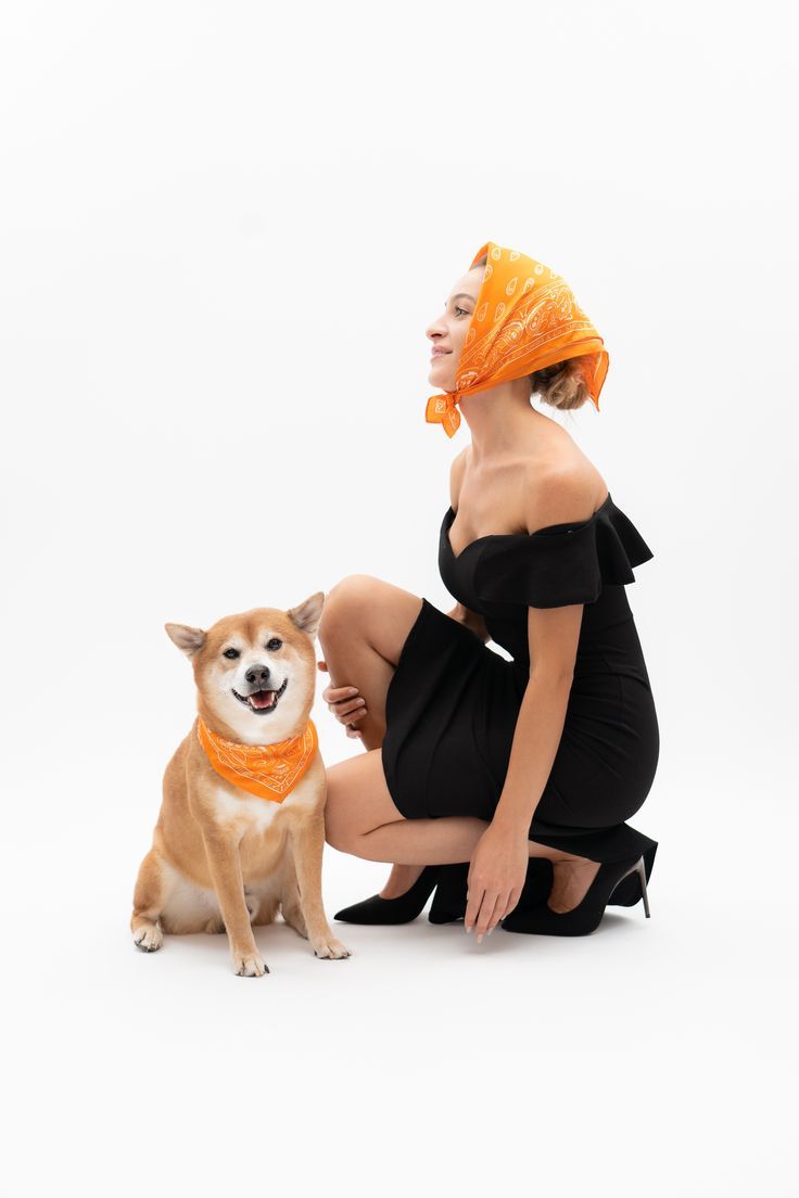 a woman kneeling down next to a small dog wearing a bandana on her head