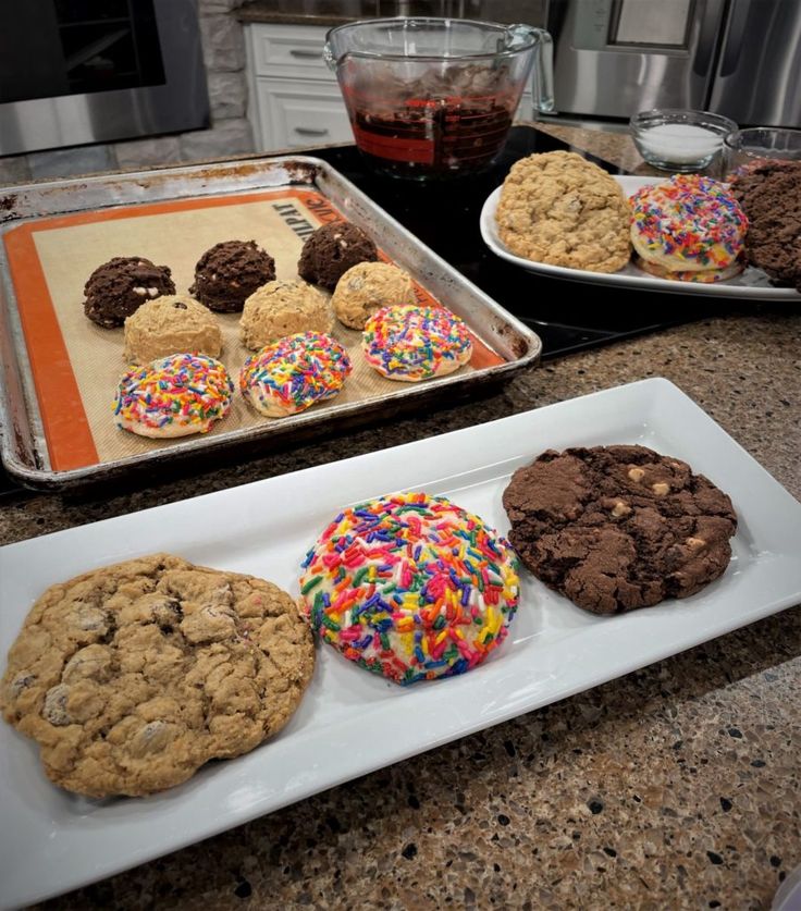 three trays of cookies on a kitchen counter