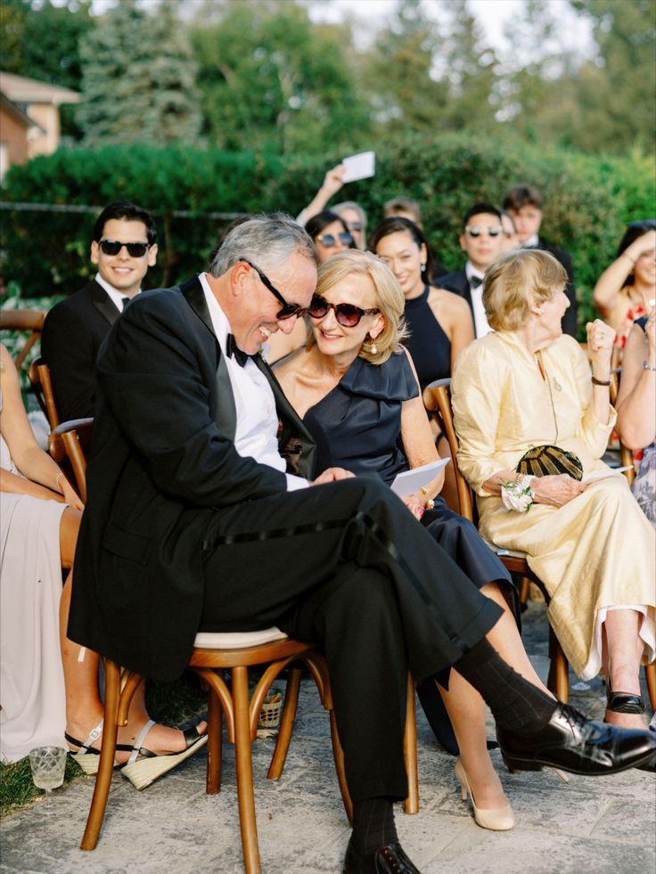 an older couple sitting next to each other in front of a large group of people