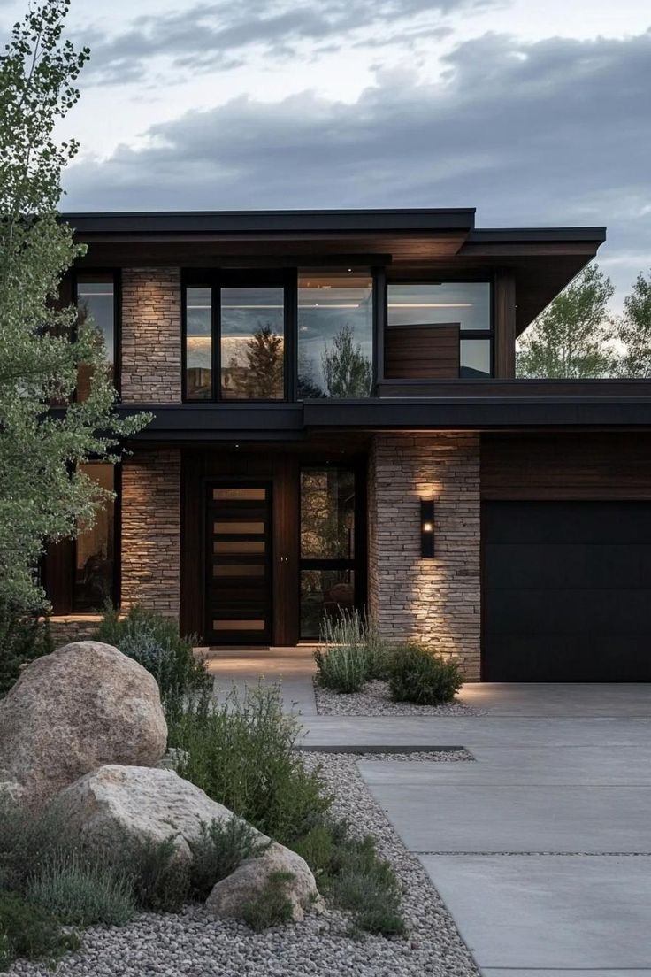 a modern house with large rocks in the front yard