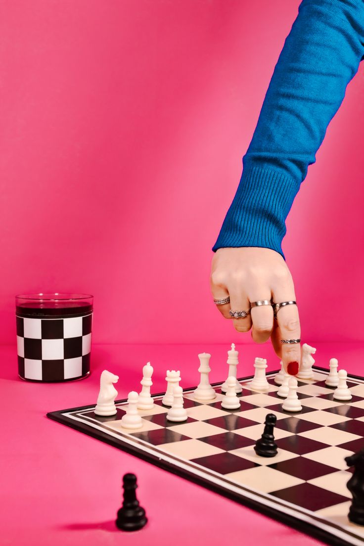 a person is playing chess on a pink surface with black and white checkered pieces