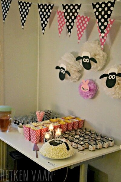 a table topped with cupcakes and cake next to a wall covered in black and white polka dots