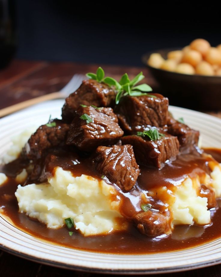 a white plate topped with meat and mashed potatoes covered in gravy next to greens