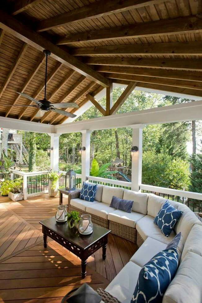 an outdoor living area with couches, tables and ceiling fans on the outside deck