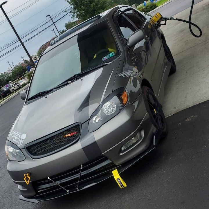 a silver car is parked on the side of the road with its door open and gas pump attached to it