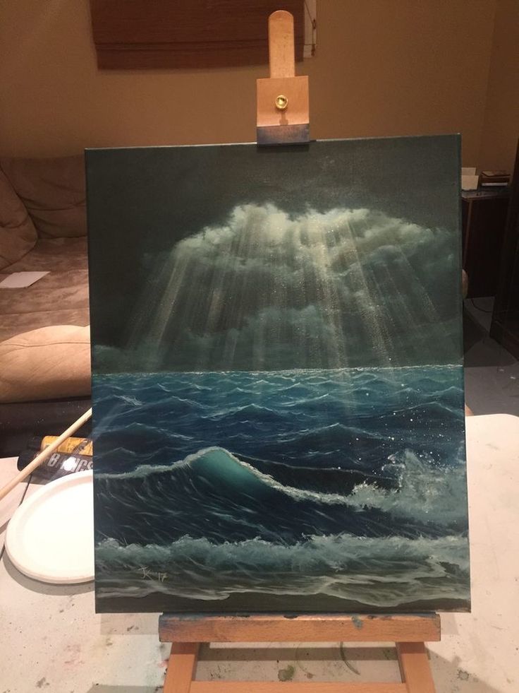 an easel with a painting on it that has sun rays coming through the clouds