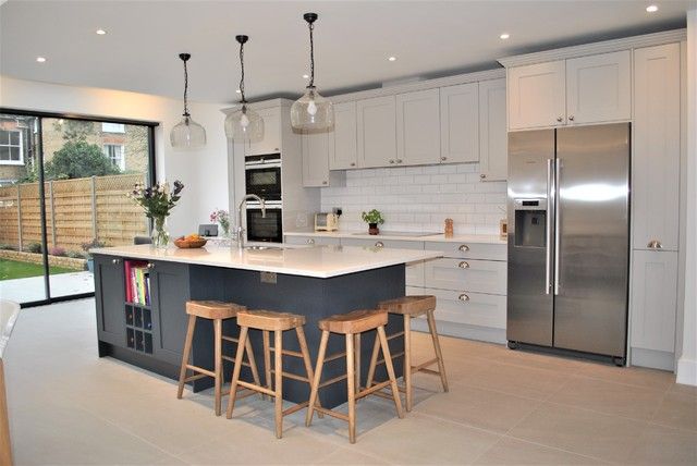 a kitchen with two stools next to an island in front of a refrigerator freezer