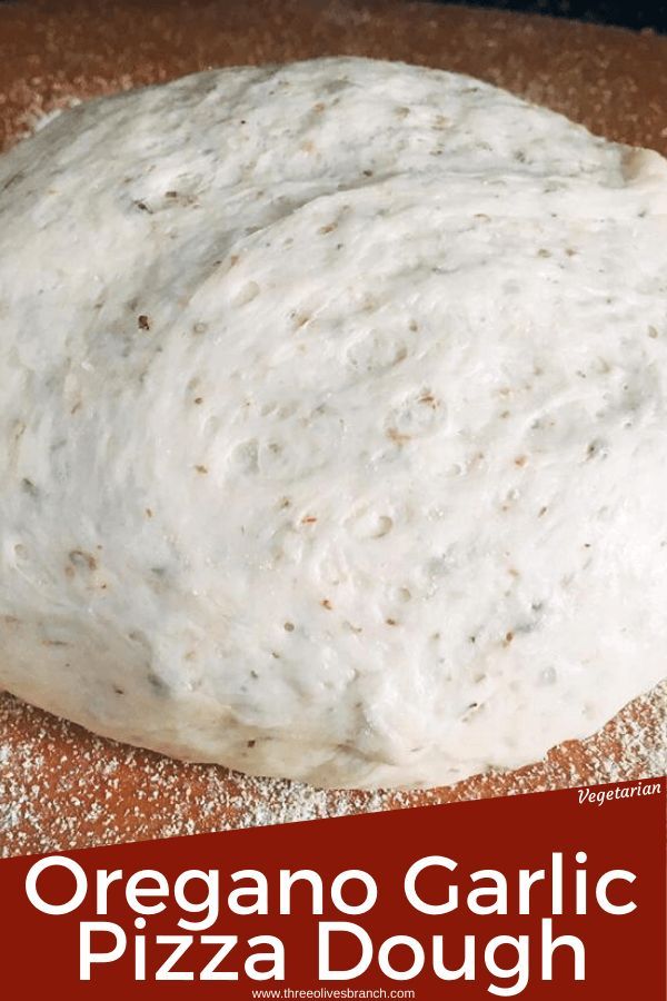 a pizza dough sitting on top of a wooden table next to a red and white sign that says oregano garlic pizza dough