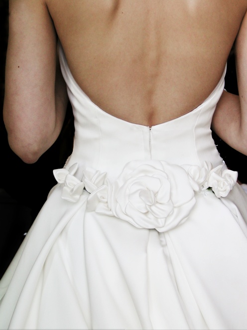 the back of a bride's wedding dress, with flowers on her lapel