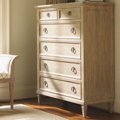 a white dresser sitting next to a window in a room with a chair and rug