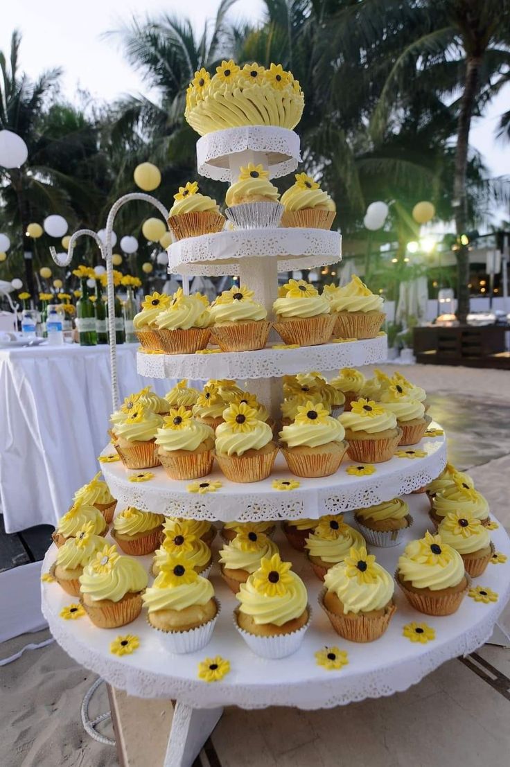 cupcakes are stacked on top of each other with yellow frosting and sunflower decorations