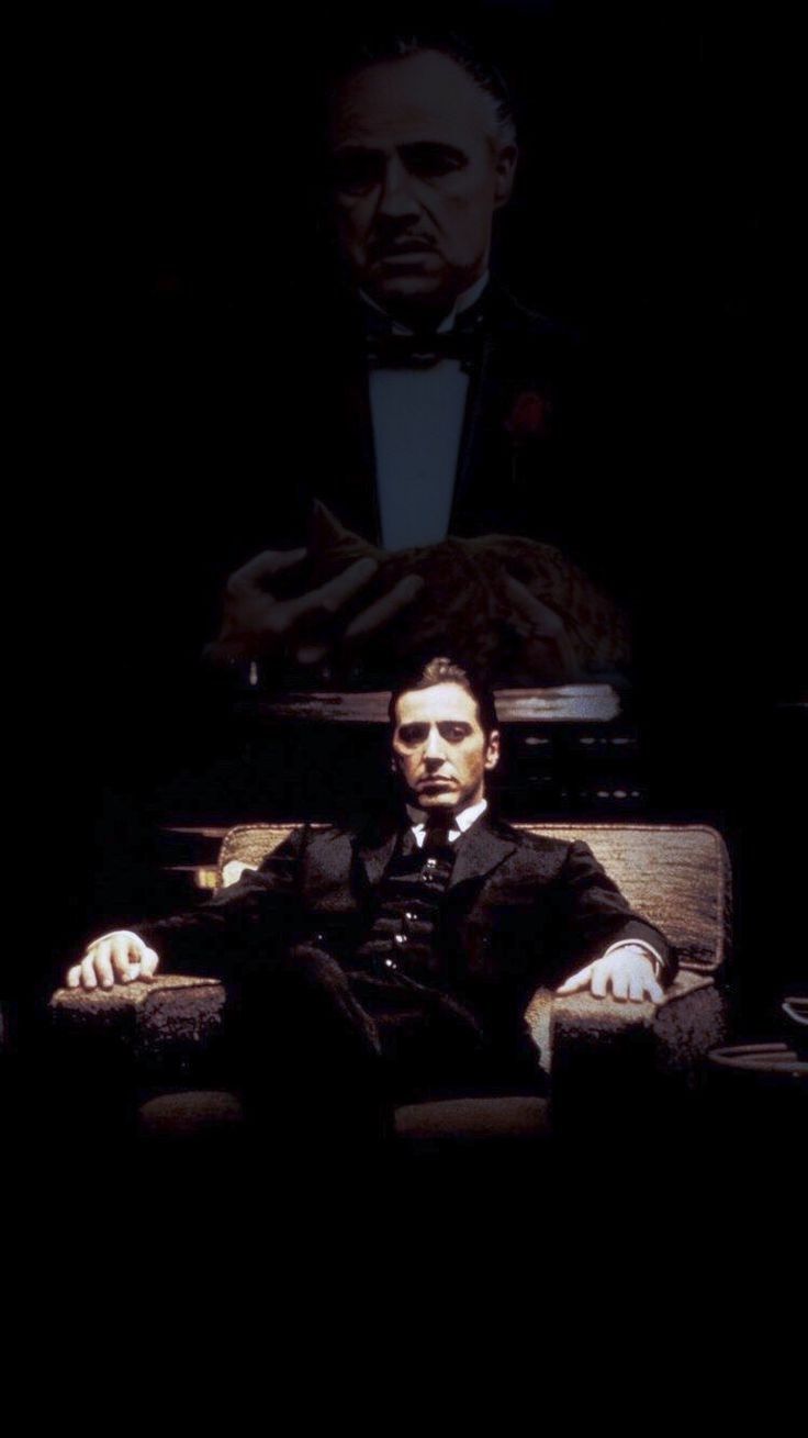 a man in a suit and tie sitting on a couch next to another man wearing a tuxedo