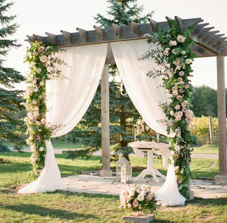 an outdoor wedding setup with white drapes and flowers