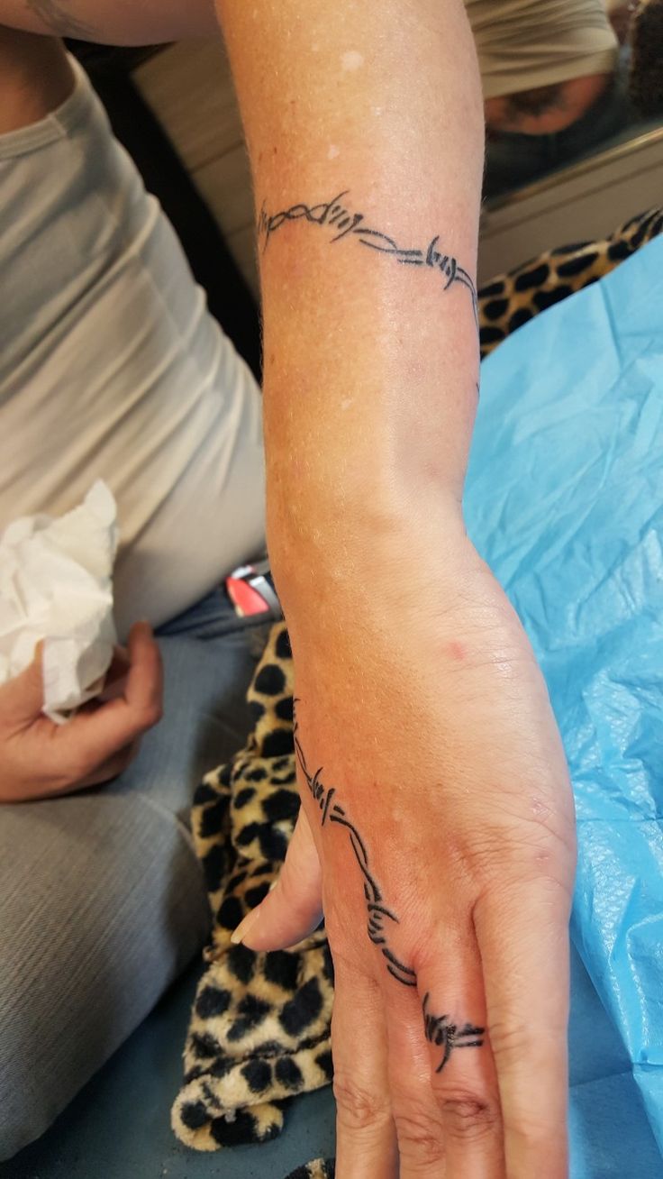 a person with a tattoo on their arm and hand holding something in the other hand