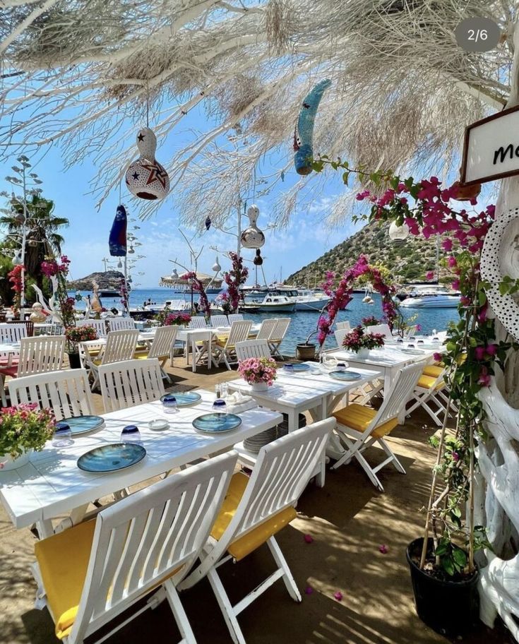 an outdoor dining area with white chairs and yellow table cloths on the tables under umbrellas