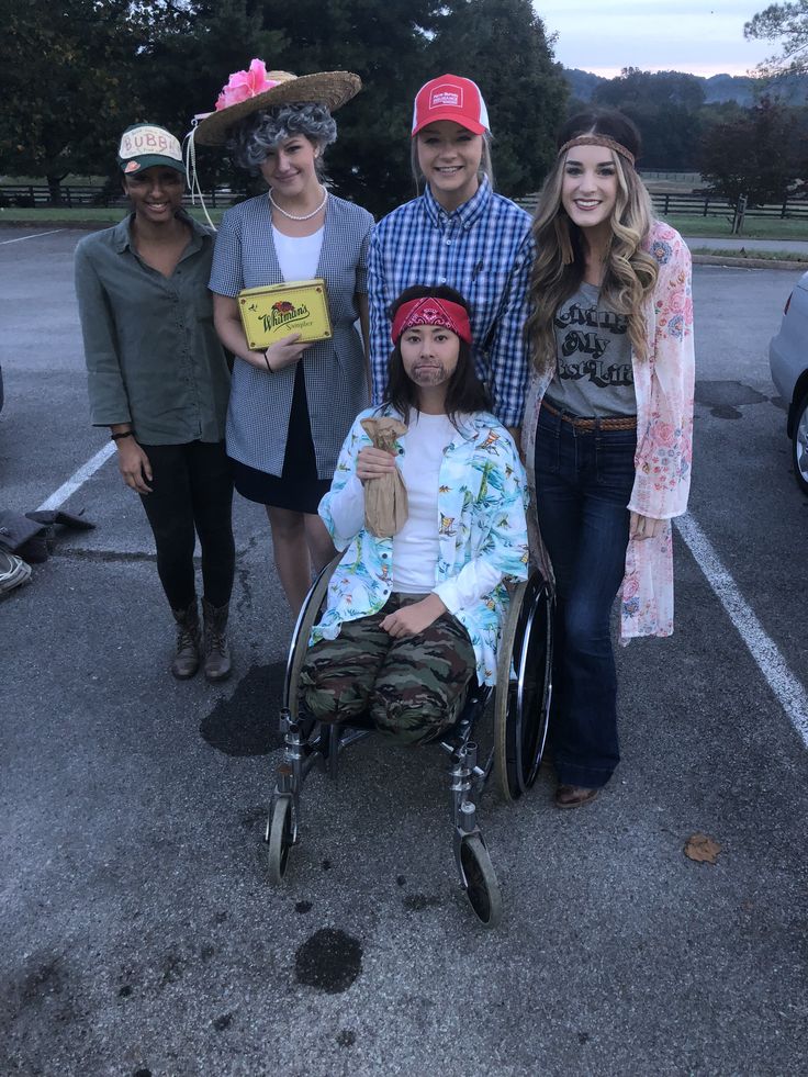 a group of people standing next to each other in a parking lot with one person in a wheel chair