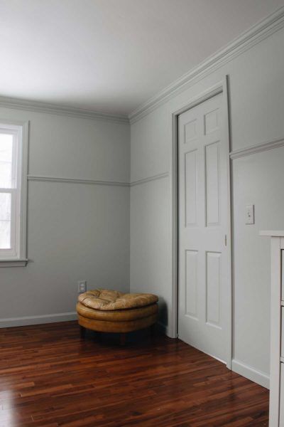 an empty room with wooden floors and white walls, including a round ottoman in the corner