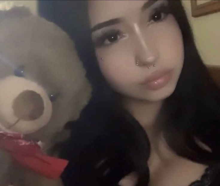 a woman with long black hair holding a teddy bear