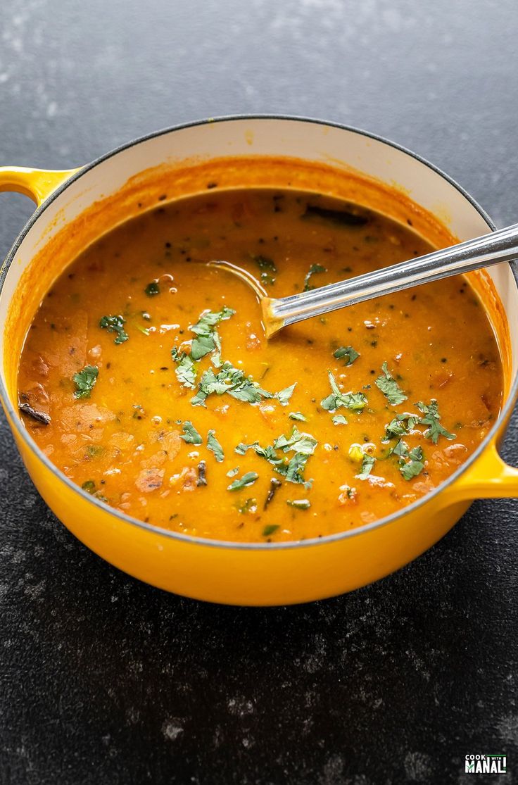 a yellow pot filled with soup and garnished with parsley on the side