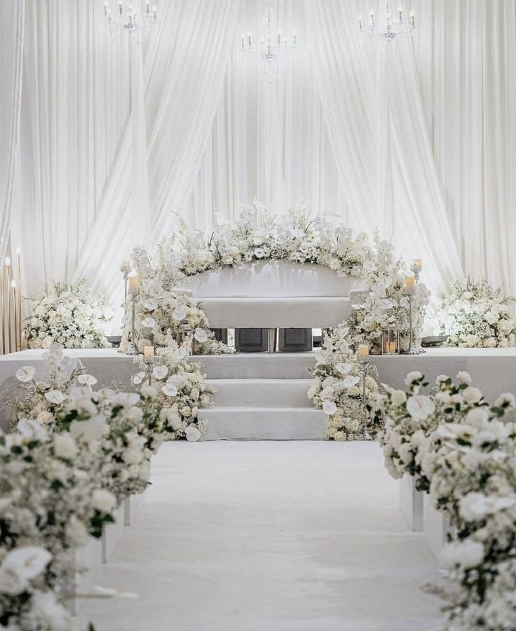 the aisle is decorated with white flowers and candles