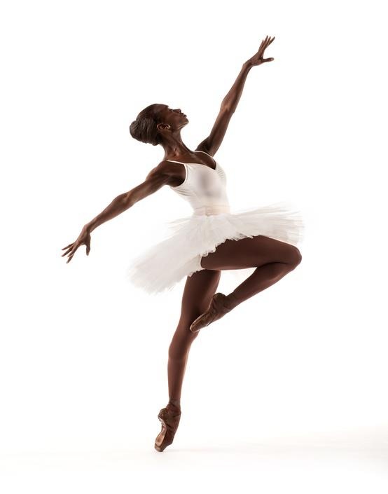 a ballerina in white tutu and black leotard posing for the camera