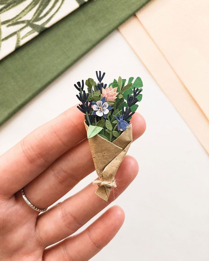 a hand holding a small bouquet of flowers in it's palm leaf wrapper