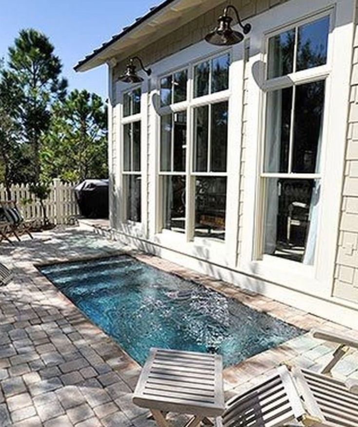 a small swimming pool in the middle of a patio with chairs and tables around it