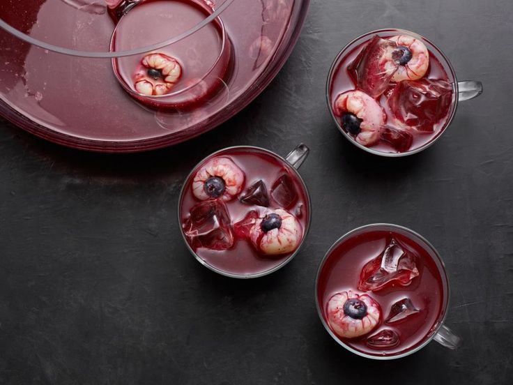 three glasses filled with liquid and fruit on top of a black table next to a red tray