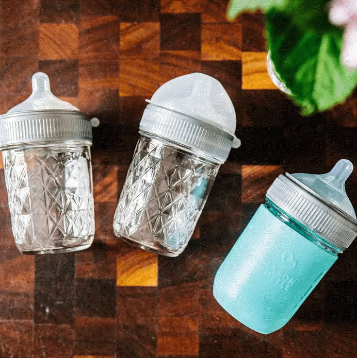 two baby bottles sitting on top of a wooden table