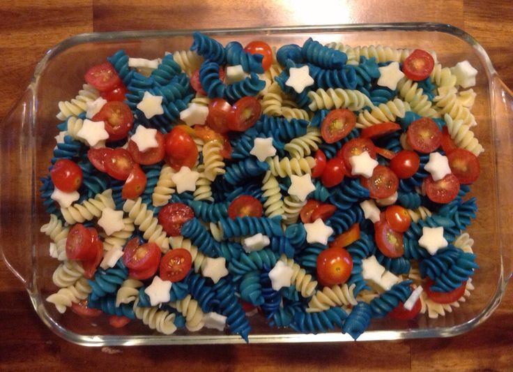 pasta with tomatoes, cheese and stars on it in a glass dish sitting on a wooden table