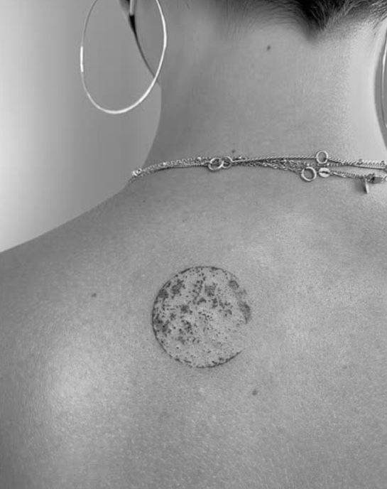 the back of a woman's neck with a circle tattoo on it