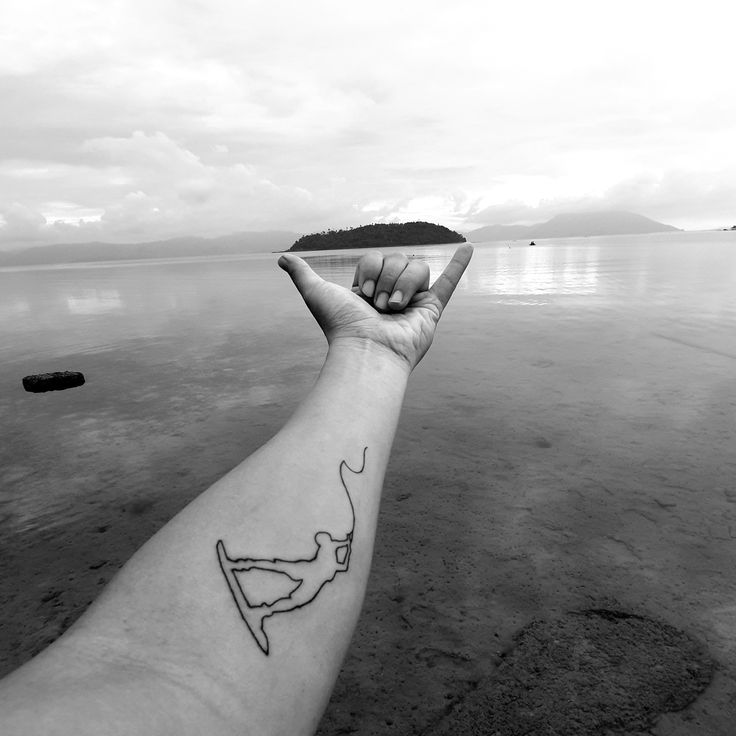 a person's arm with a small tattoo on it and the water in the background