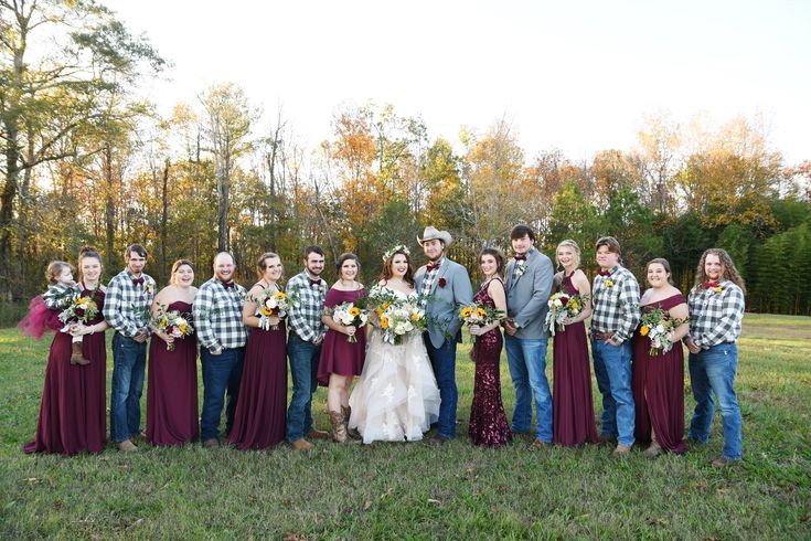 a group of people standing next to each other in a field with trees behind them