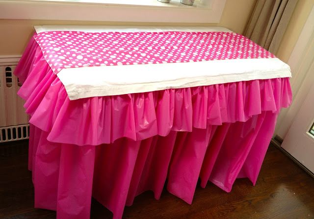 a pink and white polka dot tablecloth on top of a wooden floor next to a radiator